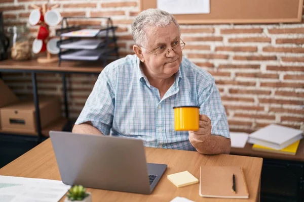 中年白发苍苍的生意人在办公室用笔记本电脑喝咖啡 — 图库照片