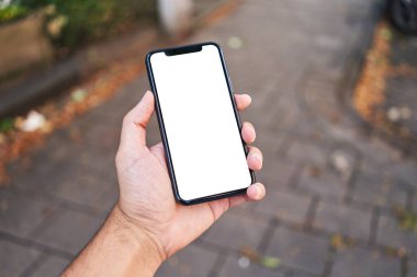 Elinde akıllı telefon tutan adam sokakta beyaz beyaz ekran gösteriyor