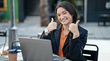 Genç, güzel, İspanyol bir iş adamı. Laptop kullanıyor. Kahve dükkanının terasında el kol hareketi yapıyor.