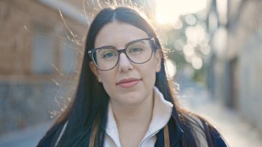 Sırt çantalı genç İspanyol kadın turist sokakta gülümsüyor.