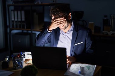 Geceleri ofiste çalışan Latin asıllı genç bir adam. Gülümsüyor ve gülümsüyor. Gözleri şaşkınlık için kapatıyordu. kör kavram. 