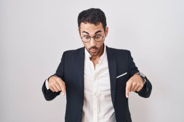 Beyaz arka planda duran yakışıklı İspanyol bir adam parmaklarını göstererek reklamını yapıyor, şaşırmış bir yüz ve açık bir ağız. 