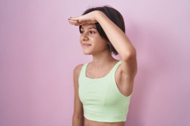 Pembe arka planda duran genç kız çok mutlu ve gülümsüyor. Çok uzaklara bakıyor. arama kavramı. 