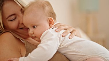 Anne ve kızı yatakta uzanıp, yatak odasında sarılıyorlar.