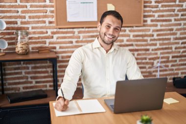 Young man business worker using laptop writing on notebook at office