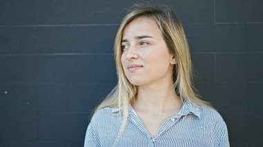 Sarışın genç bir kadın izole edilmiş siyah arka planda kendine güvenen bir şekilde gökyüzüne bakıyor.