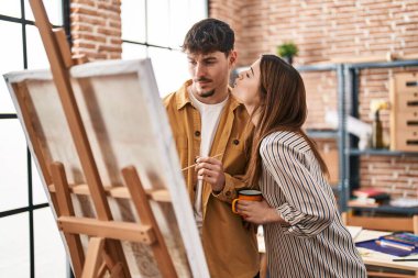 Mand and woman artist couple drinking coffee drawing at art studio