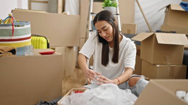 Genç, güzel, İspanyol bir kadın yeni evinde akıllı telefonuyla tartışıyor.