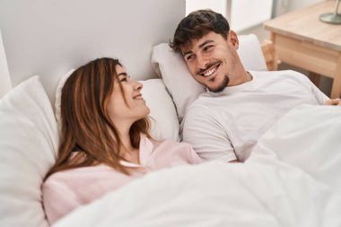 Kadın ve erkek yatak odasında yatarken gülümsüyor.
