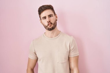 Pembe arka planda sakallı İspanyol bir adam dudaklarıyla balık suratı yapıyor, çılgınca ve komik bir jest. Komik ifade. 