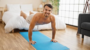 Genç İspanyol adam antrenman yapıyor. Yatak odasında gülümsüyor.