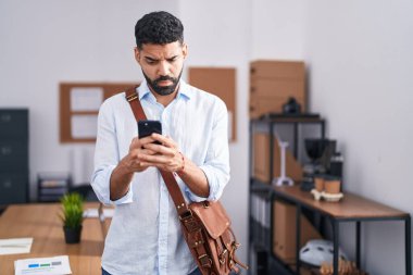 Ofiste akıllı telefon kullanan sakallı, kafası karışık ve bihaber İspanyol bir adam. şüphe kavramı. 