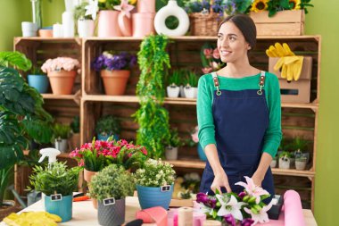 Young beautiful hispanic woman florist make bouquet of flowers at flower shop