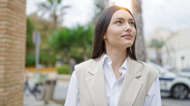 Young beautiful hispanic woman smiling confident looking to the side at street