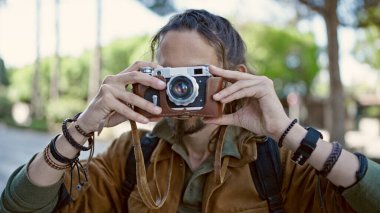 Sırt çantalı genç İspanyol turist sokakta fotoğraf çekiyor.