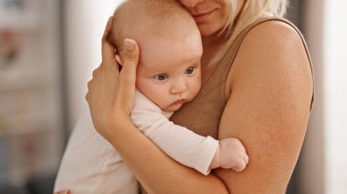 Mother and daughter hugging each other standing at home