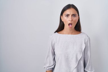 Beyaz arka planda duran genç İspanyol kadın şok olmuş gibi, şüpheci ve alaycı görünüyor, ağzı açık kalınca şaşırıyor. 