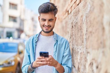 Sokakta akıllı telefon kullanan, kendine güvenen genç bir İspanyol.