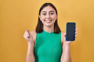 İspanyol kız elinde akıllı telefonuyla gururla bağırıyor zaferi ve başarıyı kutluyor. 