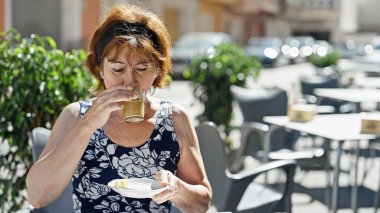 Orta yaşlı kadın kahve içiyor kahve dükkanının terasında oturuyor.