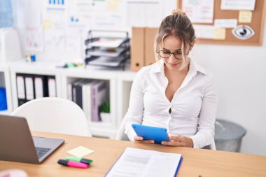 Ofiste dokunmatik ped kullanan genç sarışın bir iş kadını.