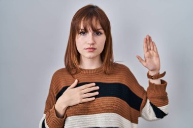 Soyutlanmış arka planda çizgili süveter giyen genç ve güzel bir kadın. Göğüs ve avuçlar açık küfür ediyor. Sadakat yemini ediyor. 