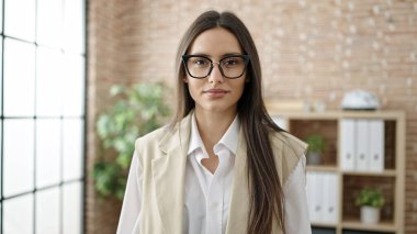 Young beautiful hispanic woman business worker standing with relaxed expression at office