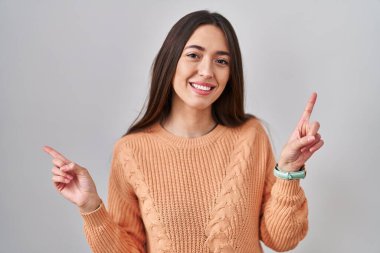 Beyaz arka planda duran esmer bir kadın farklı yönleri gösteren kendine güvenen bir şekilde gülümsüyor. reklam için kopyalama alanı 