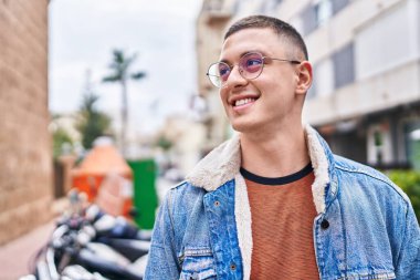 Young hispanic man smiling confident looking to the side at street