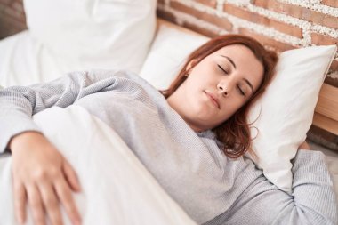 Genç, güzel, iri yarı bir kadın yatakta uzanıyor ve yatak odasında uyuyor.