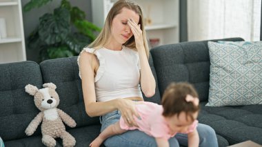 Anne ve kızı evdeki kanepede yorgun oturuyorlar.