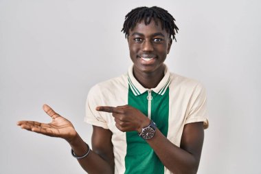 Münzevi arka planda duran Afrikalı adam kameraya hayret ediyor ve gülümsüyor.. 