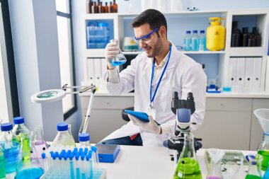 Laboratuvarda dokunmatik ped kullanarak sıvıyı ölçen genç İspanyol bilim adamı.