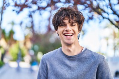 Parkta kendinden emin gülümseyen İspanyol genç adam.