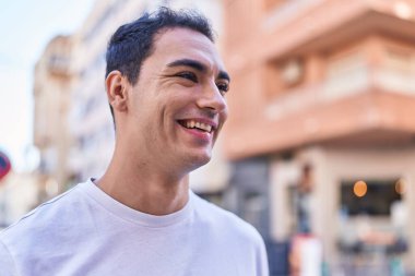 Young hispanic man smiling confident looking to the side at street