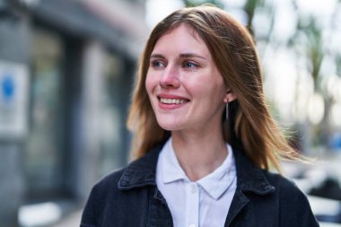 Young blonde woman smiling confident looking to the side at street