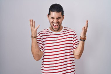 Uzun saçlı İspanyol bir adam, izole edilmiş arka planda duruyor. Başarı için deli ve çılgınlığı kutluyor. Kollarını kaldırmış, gözlerini kapatmış heyecanlı çığlıklar atıyor. Kazanan konsept 