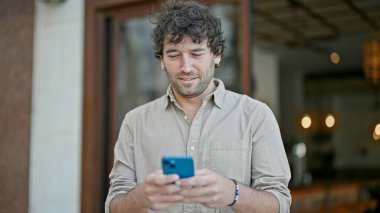 Sokakta akıllı telefon kullanan, kendine güvenen genç bir İspanyol.