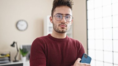 Genç İspanyol iş adamı elinde ciddi bir yüzle akıllı telefon tutuyor.