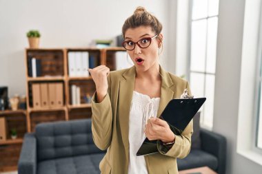 Muayenehanede çalışan genç bir kadın elleri yana doğru işaret ederek şaşırdı, ağzı açık hayret içinde kaldı.. 