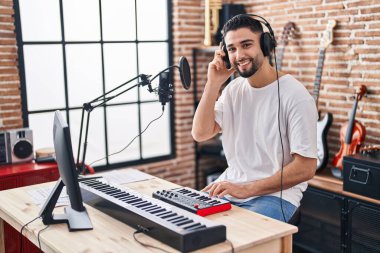 Genç Arap müzisyen müzik stüdyosunda piyano klavyesi çalıyor.