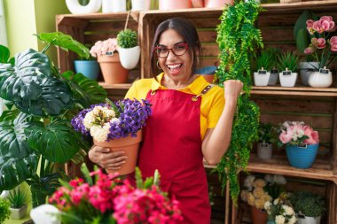 Çiçekçi dükkanında çalışan genç Arap kadın elinde çiçeklerle gururla bağırıyor zaferi ve başarıyı kutluyor. 