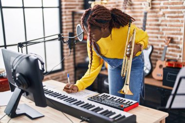 Afrikalı Amerikalı kadın müzisyen müzik stüdyosunda trompet besteliyor.