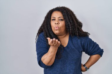 Ayrıca beyaz arka planda dikilen boyunda bir İspanyol kadın kameraya bakıp havada öpüşürken güzel ve seksi görünüyor. aşk ifadesi. 