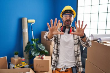 Evde sakallı, korku ifadesinden korkan ve dehşete düşmüş genç bir İspanyol adam. El hareketini durdur, şok içinde bağır. panik konsepti. 