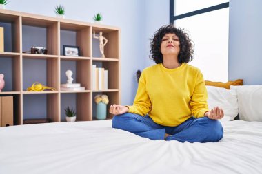 Genç ve güzel İspanyol kadın yoga yapıyor. Yatak odasında oturuyor.