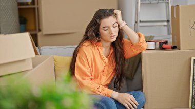 Yeni evinde ciddi bir ifadeyle kanepede oturan güzel İspanyol bir kadın.