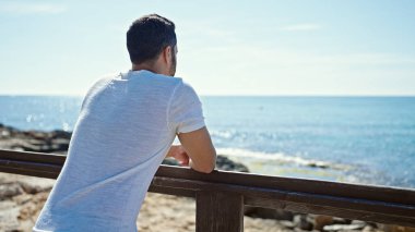 Genç İspanyol adam deniz kıyısında geriye yaslanıyor.