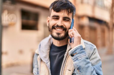 Genç İspanyol adam gülümsüyor. Kendine güveniyor. Sokakta akıllı telefondan konuşuyor.