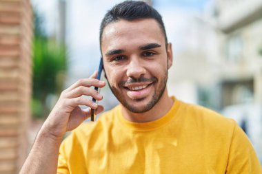 Genç İspanyol adam gülümsüyor. Kendine güveniyor. Sokakta akıllı telefondan konuşuyor.